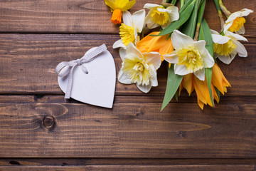 Background with fresh daffodils and tulips and decorative heart
