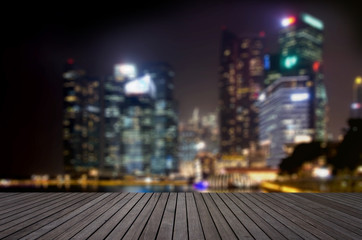 Fototapeta na wymiar Wood floor in dark grey color tone with blurred abstract background of Singapore night lights city view on riverfront