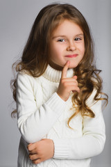 Portrait of little girl thinking, over a gray background