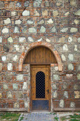 Old wooden door in the wall of stone 