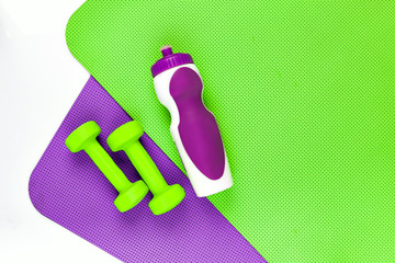 Yoga mat. Purple and green mat workouts. Two green dumbbells.
