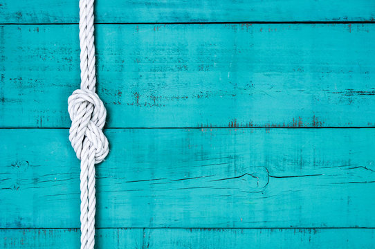 White rope with knot on blank antique teal blue rustic wooden background