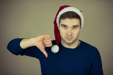 disappointed man in santa cap showing thumbs down