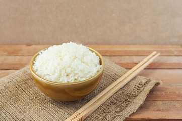 White rice in brown bowl with wood chopsticks