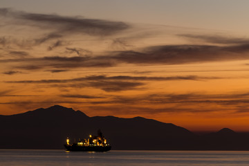Naklejka na ściany i meble Fisherman on the boat over dramatic sunset, male on vessel, beau