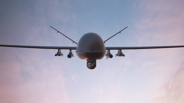 Military predator drone flying at sunset. Armed intelligent unmanned vehicle.