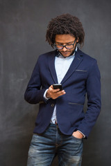 Typing message. Handsome young man with afro hair in shirt holdi
