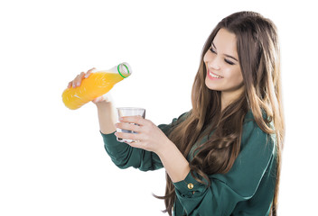 beautiful girl with dark hair pouring from a bottle into a glass of orange juice on a white background