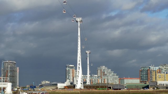 Wide view of cable cars over the river Thames in the financial district of the Docklands in London with dark clouds