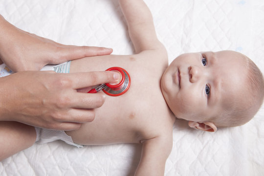 Pediatrician examines three months baby boy using a stethoscope