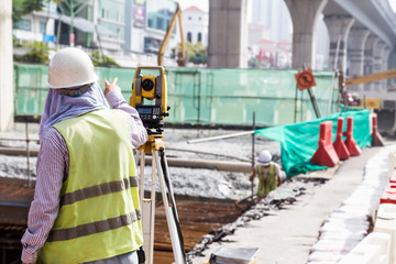 Naklejka premium Engineer instructing while operating dumpy automatic level instr