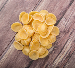 Dried orecchiette pasta or ear shape pasta over wooden background