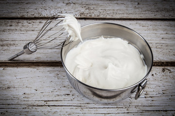 Whisk and bowl with whipped cream
