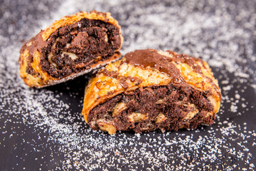 Traditional chocolate rugelach with sugar on dark surface