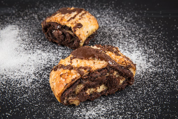 Traditional chocolate rugelach with sugar on dark surface