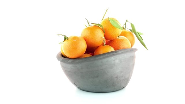 Tangerines on clay bowl isolated on white background