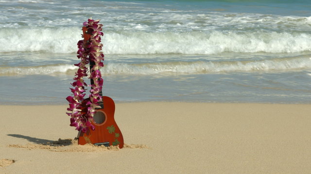 Hawaii concept with ukulele and Lei on beach. Traditional Hawaiian instrument and flower wreath or garland on perfect sandy beach on Oahu.