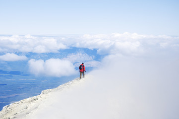Lone hiker is walking on the clouds