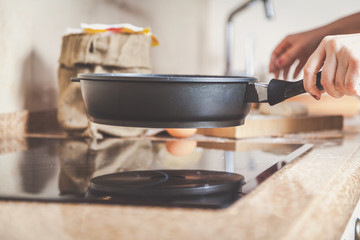 Female hand putting pan on stove