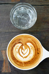 cup of latte art coffee on wooden background