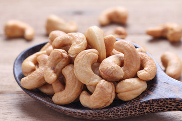 Cashew nuts in wooden ladle on wooden background