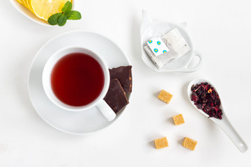 Cup of tea with cube sugar and chocolate on a white table.Top view.