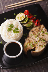 Baked steak of fish, rice and soy sauce close-up. vertical top view
