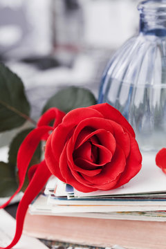 Red rose flower with a stack of postcard, retro photos and vintage book