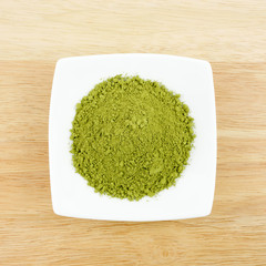 The Japanese matcha green tea powder on the mini white dish on wooden board.