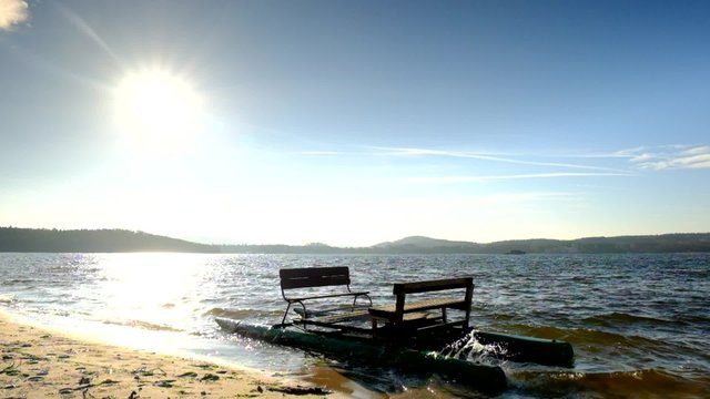 Abandoned old rusty paddle boat stuck on sand of beach. Wavy water level, island on horizon. Autumn weather at coastline 