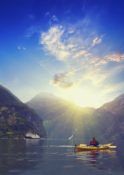 Kayaker  at Geiranger fjord bay at sunset at Norway. Extreme travel background