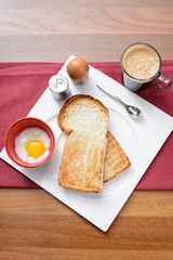 Top view of breakfast set of tea, toast bread and half-boiled egg