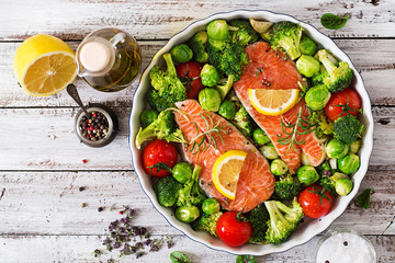Raw salmon steak and vegetables for cooking on a light wooden background in a rustic style. Top view