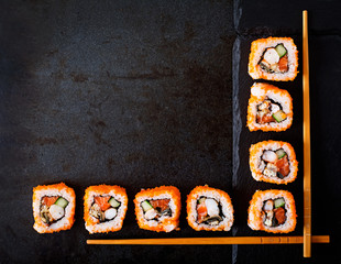 Traditional Japanese food - sushi, rolls and chopsticks for sushi on a dark background. Top view