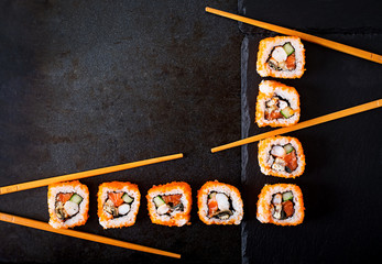 Traditional Japanese food - sushi, rolls and chopsticks for sushi on a dark background. Top view