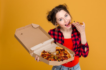 Beautiful happy young woman holding and eating pizza