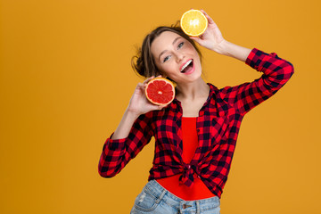 Joyful beautiful young woman holding halves of citrus fruits