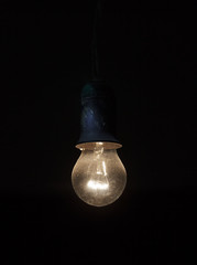 Old dusty light bulb glowing in the dark