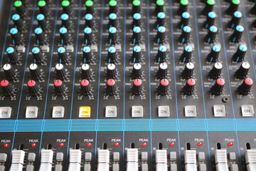 Close up of the rows of knobs and sliders on an analogue mixing