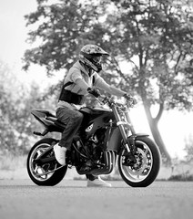Fototapeta na wymiar Ready, set, go! Low angle monochrome shot of a biker man posing on his motorcycle