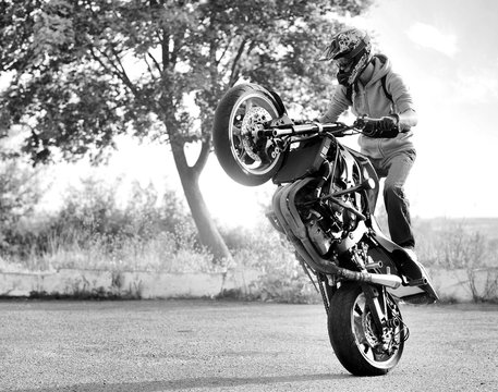 Ready to roll. Horizontal black and white soft smudged focus shot of a biker making a stunt