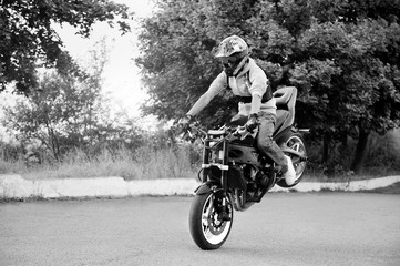 Obraz na płótnie Canvas Extreme hobby. Talented risky stuntmen riding his motorbike on the road black and white shot soft smudged focus