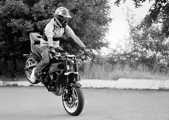 Fototapeta na wymiar Balancing gracefully. Young stuntman practicing tricks on the road monochrome soft smudged focus shot