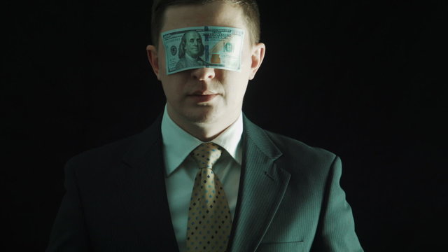 The person in a suit closes eyes by the hundred-dollar banknote 
