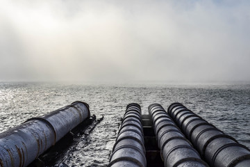 Foggy morning view of Iron pipes for water captation from the ri