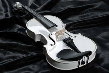 Closeup of a white violin on a background of  black satin © cwzahner