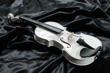 Closeup of a white violin on a background of  black satin © cwzahner