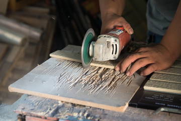 Worker using a hand circular saw to cut a tile
