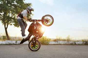 His way to impress. Shot of a stunt rider practicing for the extreme competition outdoors on sunset...
