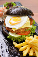 American style black burger and chips on wooden board